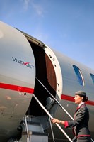 VistaJet 7500 exterior with a cabin hostess at the top of stairs