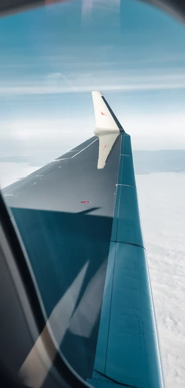 VistaJet Bombardier Global 8000 silver and red wing in the sky